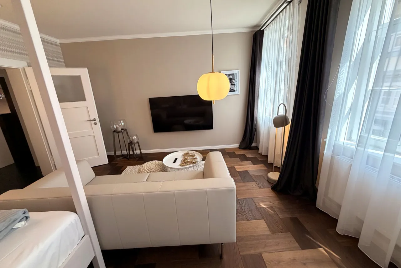 Wohnbereich mit Sofa, Fernseher und Fischgrätparkett – Logierhof Goslar Wohnung 1 in Goslar