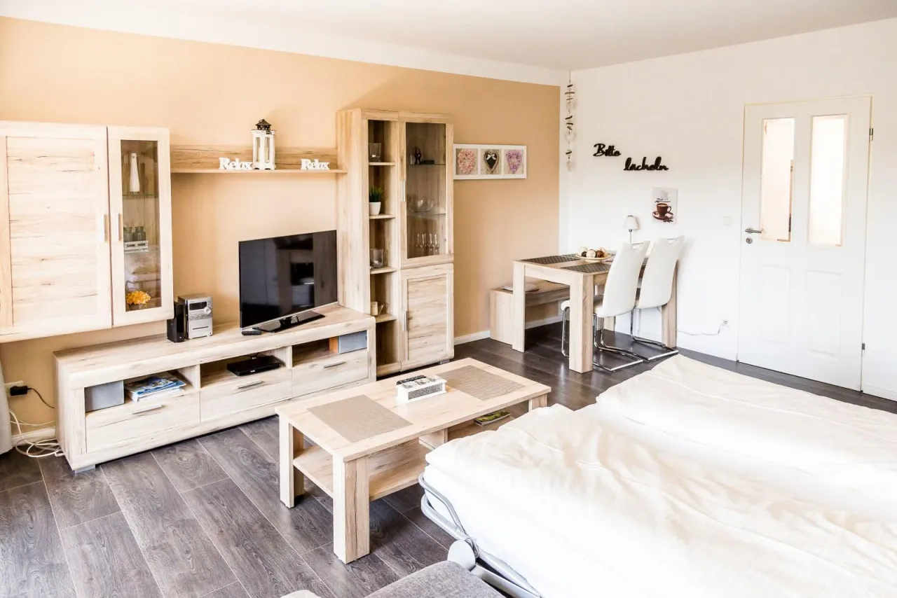 Wohn- und Schlafraum mit Schrankwand, Fernseher und Essplatz – Fewo Petra in Hahnenklee