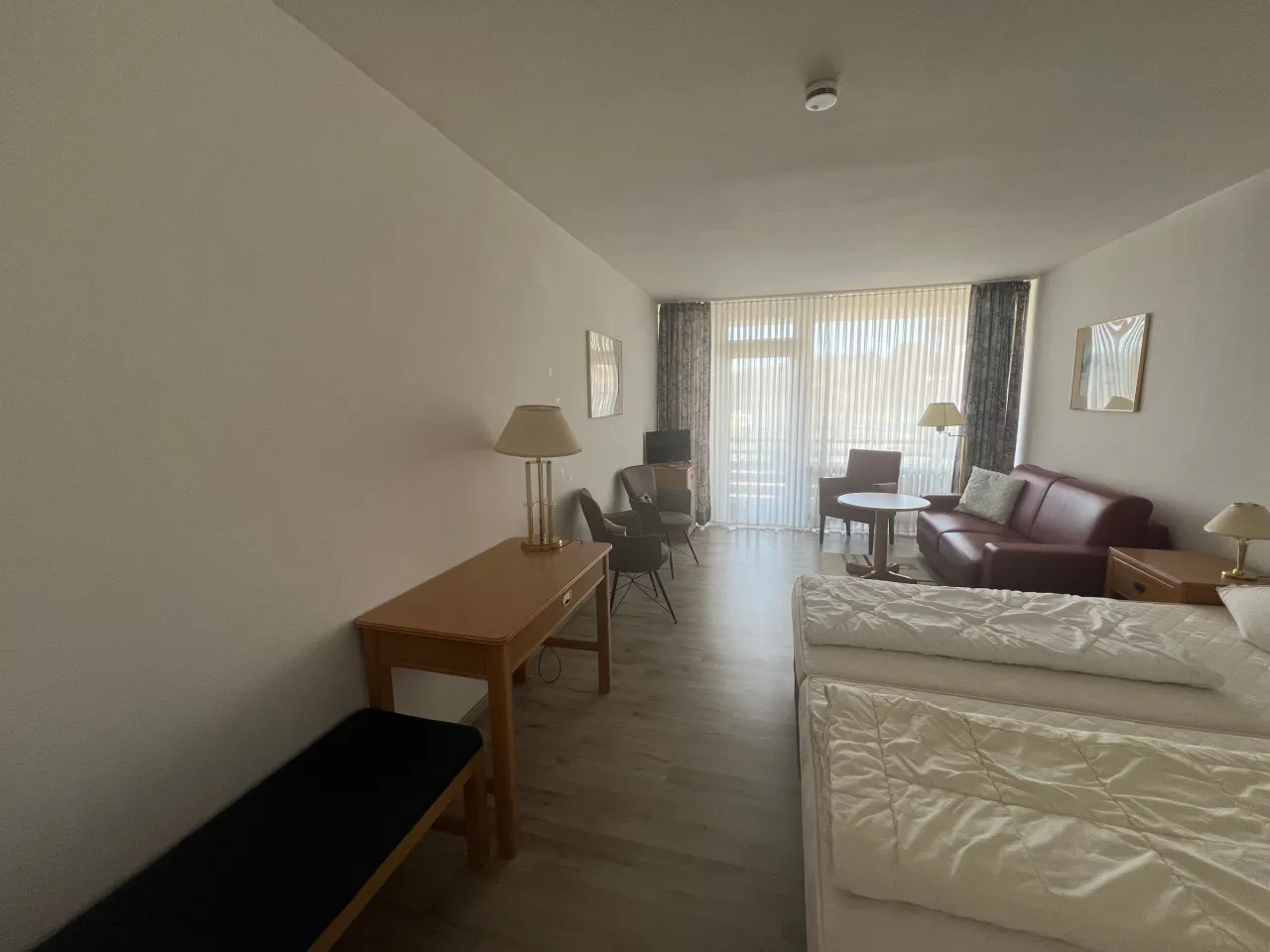 Zimmer vom Eingang aus mit Schreibtisch und Sitzecke – Haus Vier Jahreszeiten am See Die Stille in Hahnenklee