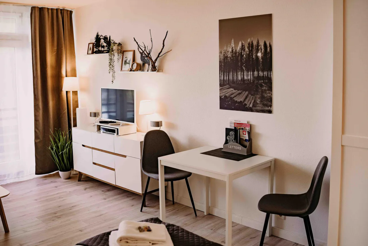 Arbeitsplatz mit Schreibtisch und Fernsehsideboard – Haus Vier Jahreszeiten am See Harzflair in Hahnenklee
