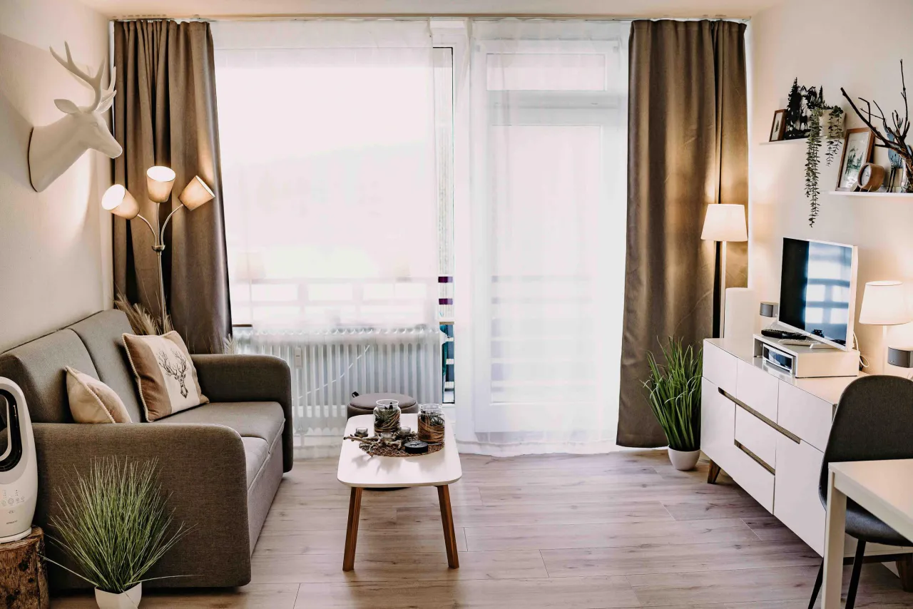 Wohnbereich mit Sofa, Fernsehsideboard und Balkontuer – Haus Vier Jahreszeiten am See Harzflair in Hahnenklee