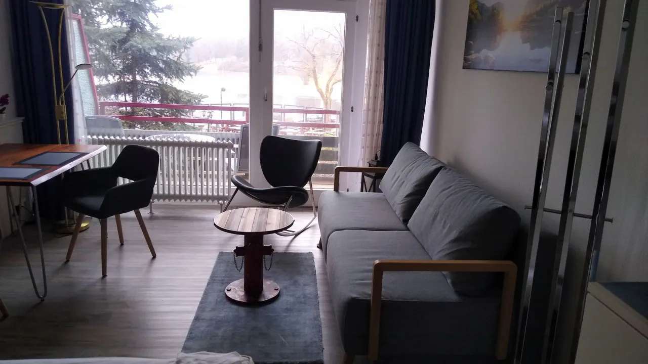 Wohnbereich mit Sofa, Esstisch und Balkonzugang – Haus Vier Jahreszeiten am See HS 715 S in Hahnenklee