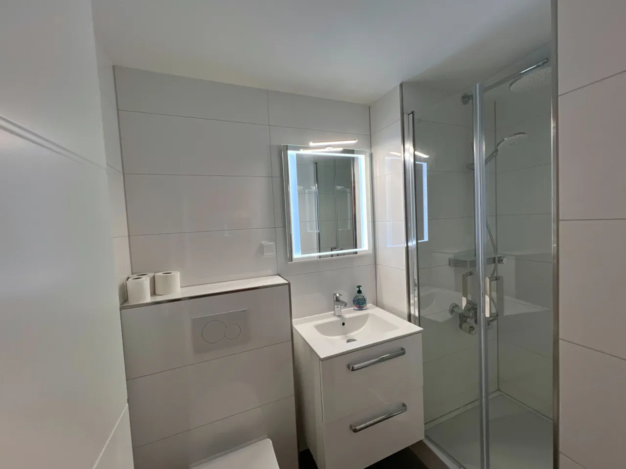 Badezimmer mit Dusche, Waschtisch und beleuchtetem Spiegel – Haus Vier Jahreszeiten am See HS 715 S in Hahnenklee