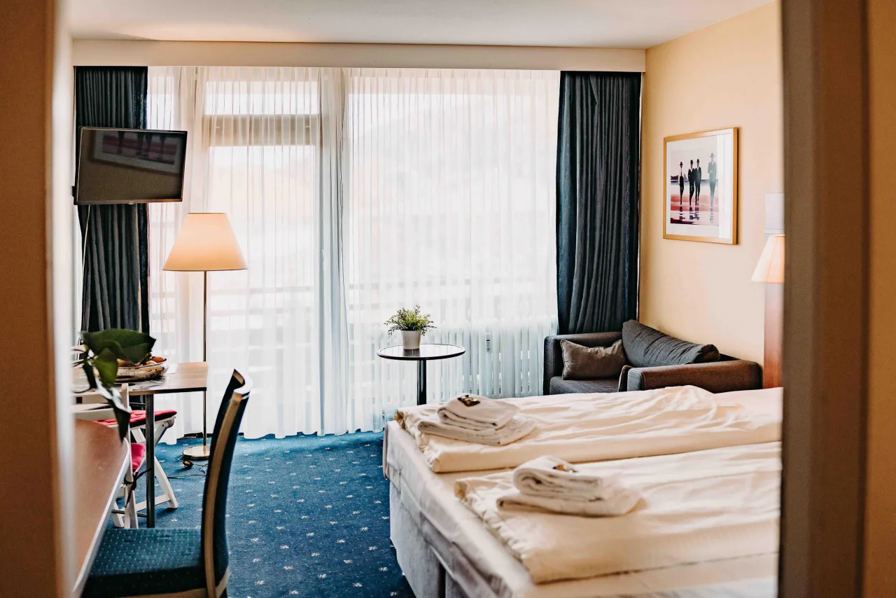 Zimmer mit Doppelbett, Sitzecke, Arbeitsplatz und Fensterfront – Haus Vier Jahreszeiten am See HS 833 in Hahnenklee