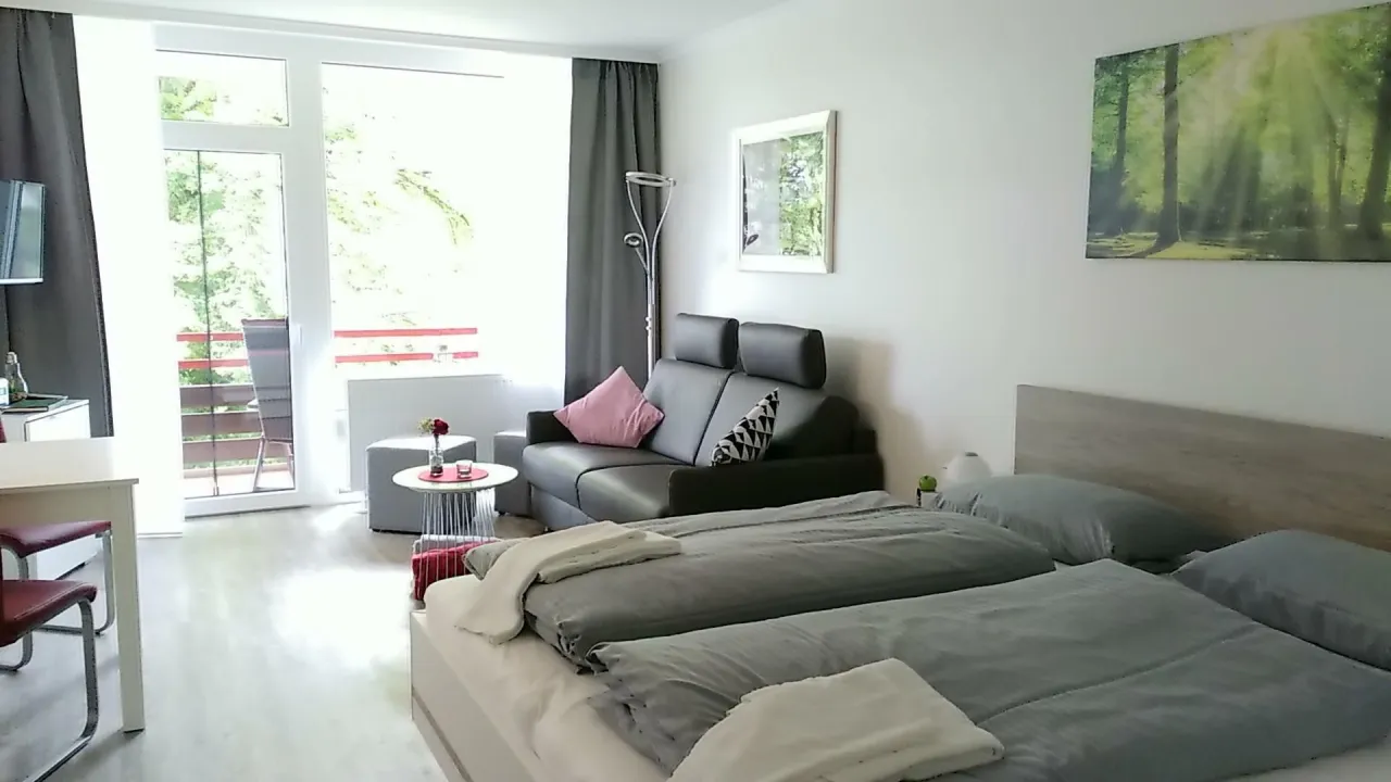 Studio mit Bett, Sofa und Balkontür – Haus Vier Jahreszeiten am See Kranich Nest 336 in Hahnenklee