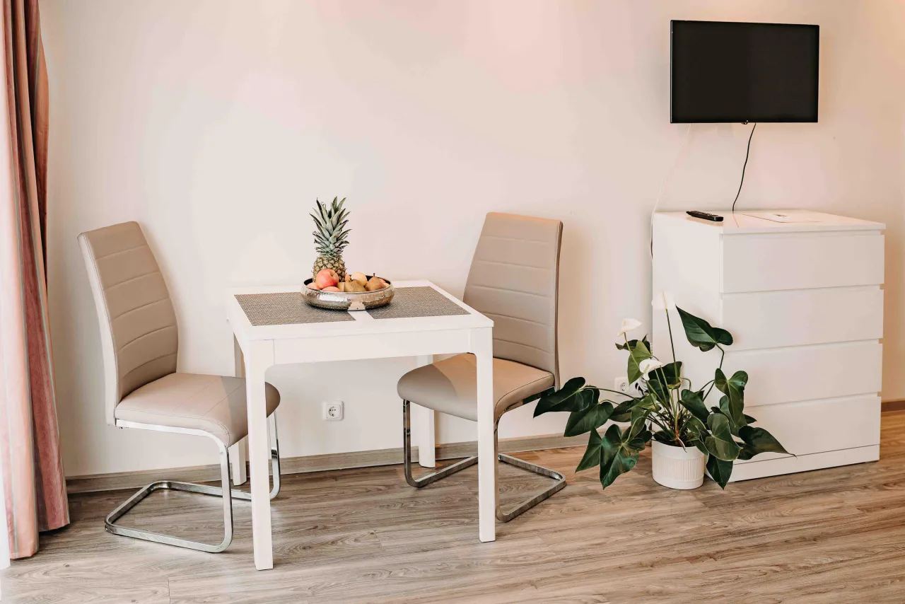 Essplatz mit Tisch, zwei Stühlen, Fernseher und Kommode – Haus Vier Jahreszeiten am See Penthouse Klee in Hahnenklee